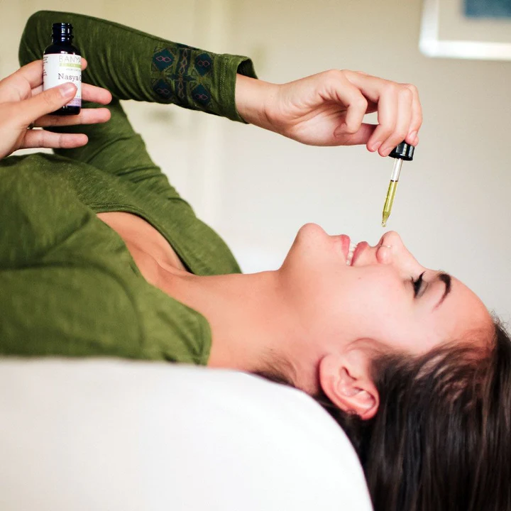 A woman putting nasya oil in her nostrils.